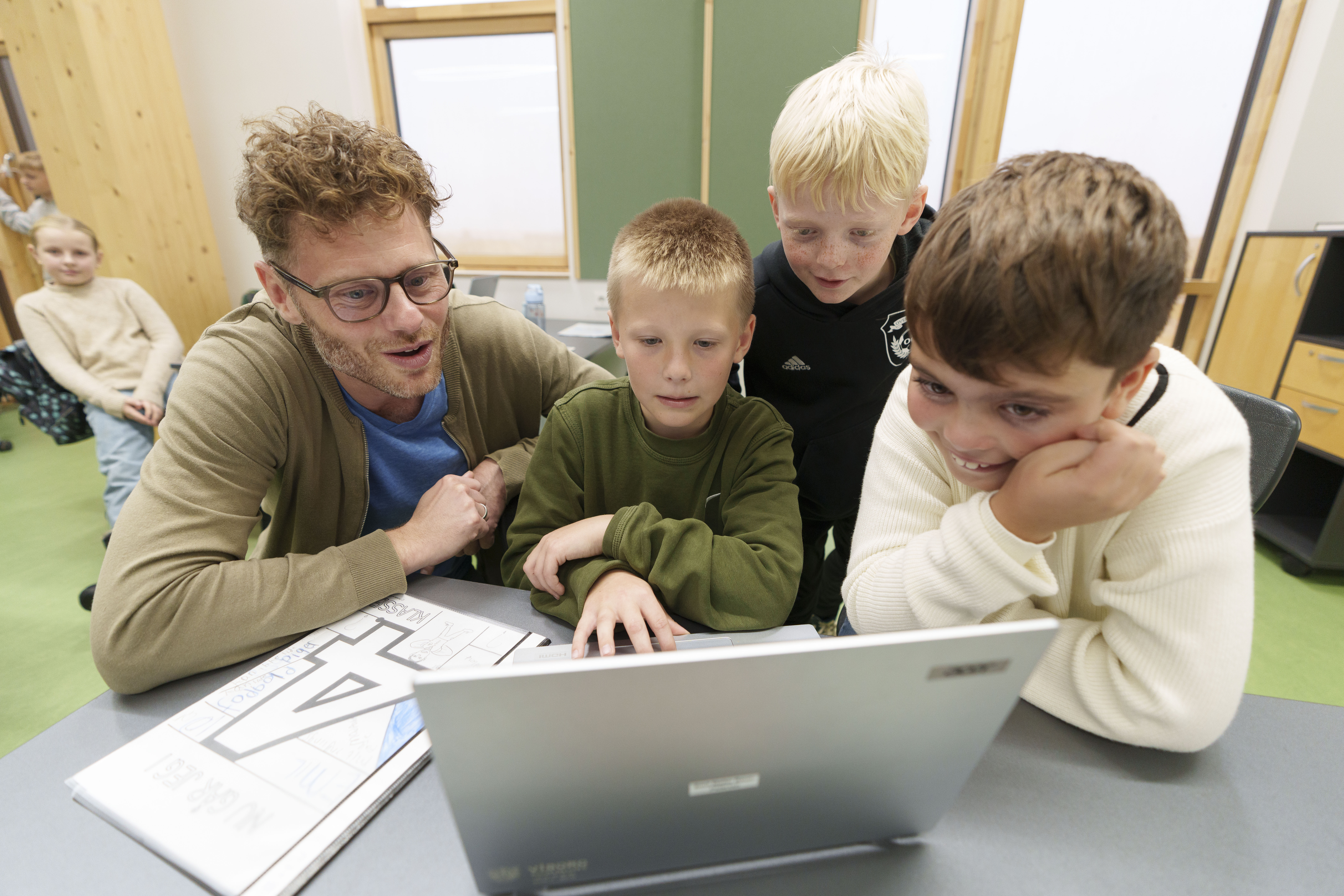 Børn i indskolingen kigger på pc sammen med voksen