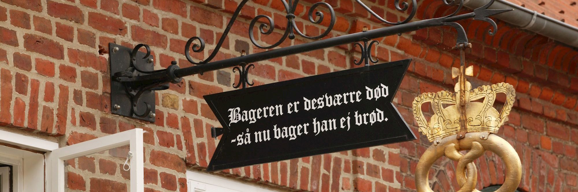 Skilt i Sct. Mogens Gade i Viborg med teksten "Bageren er desværre død - så nu bager han ej brød"