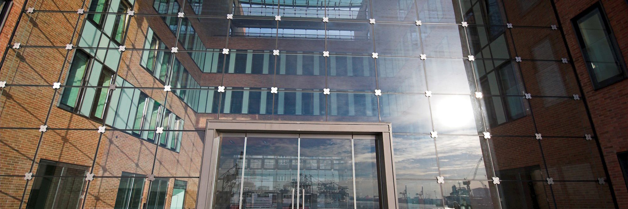 Bygningsfacade. Murstensmure og en glasfacade, er spejlerl lyset