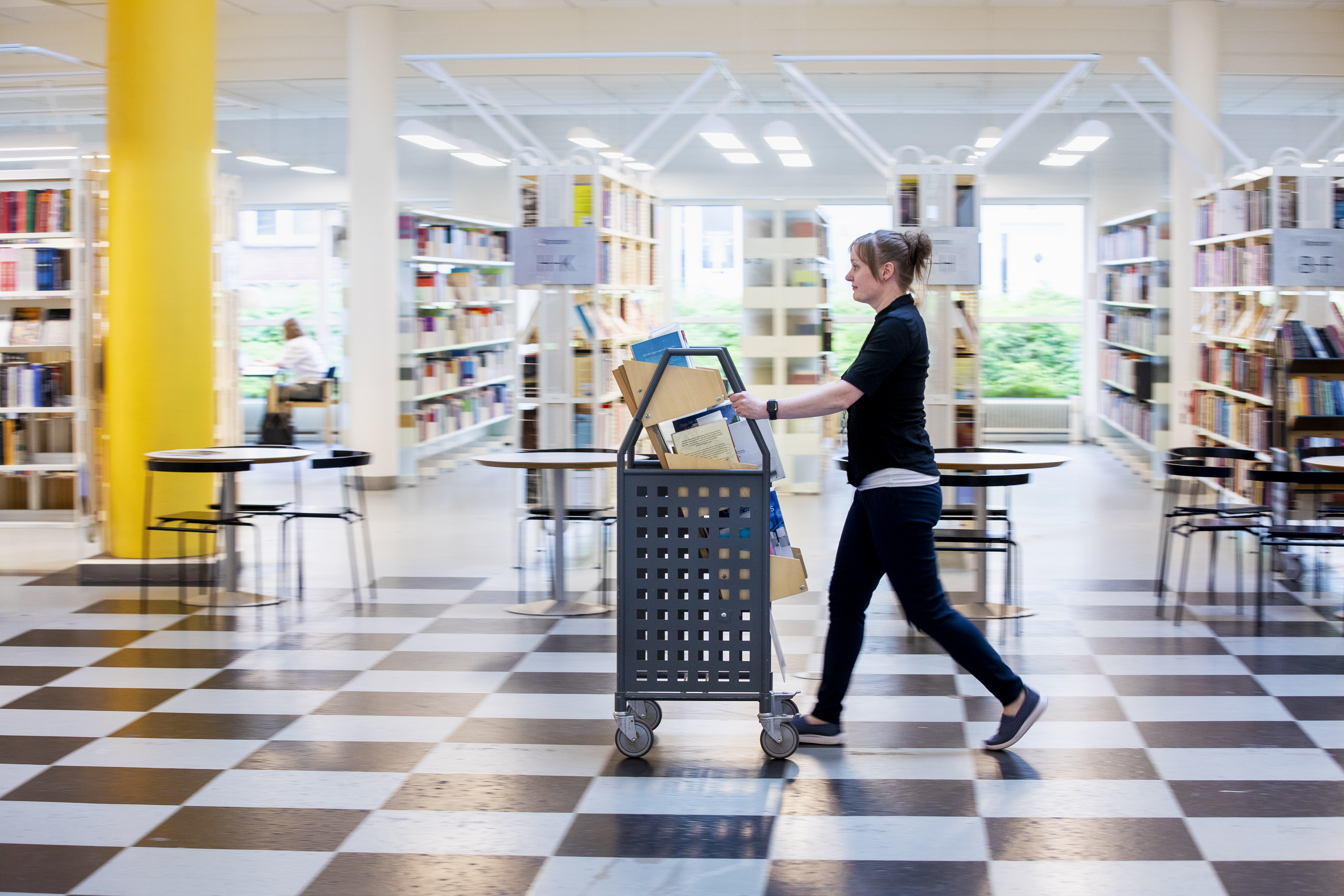 Kvinde går med bogvogn på biblioteket