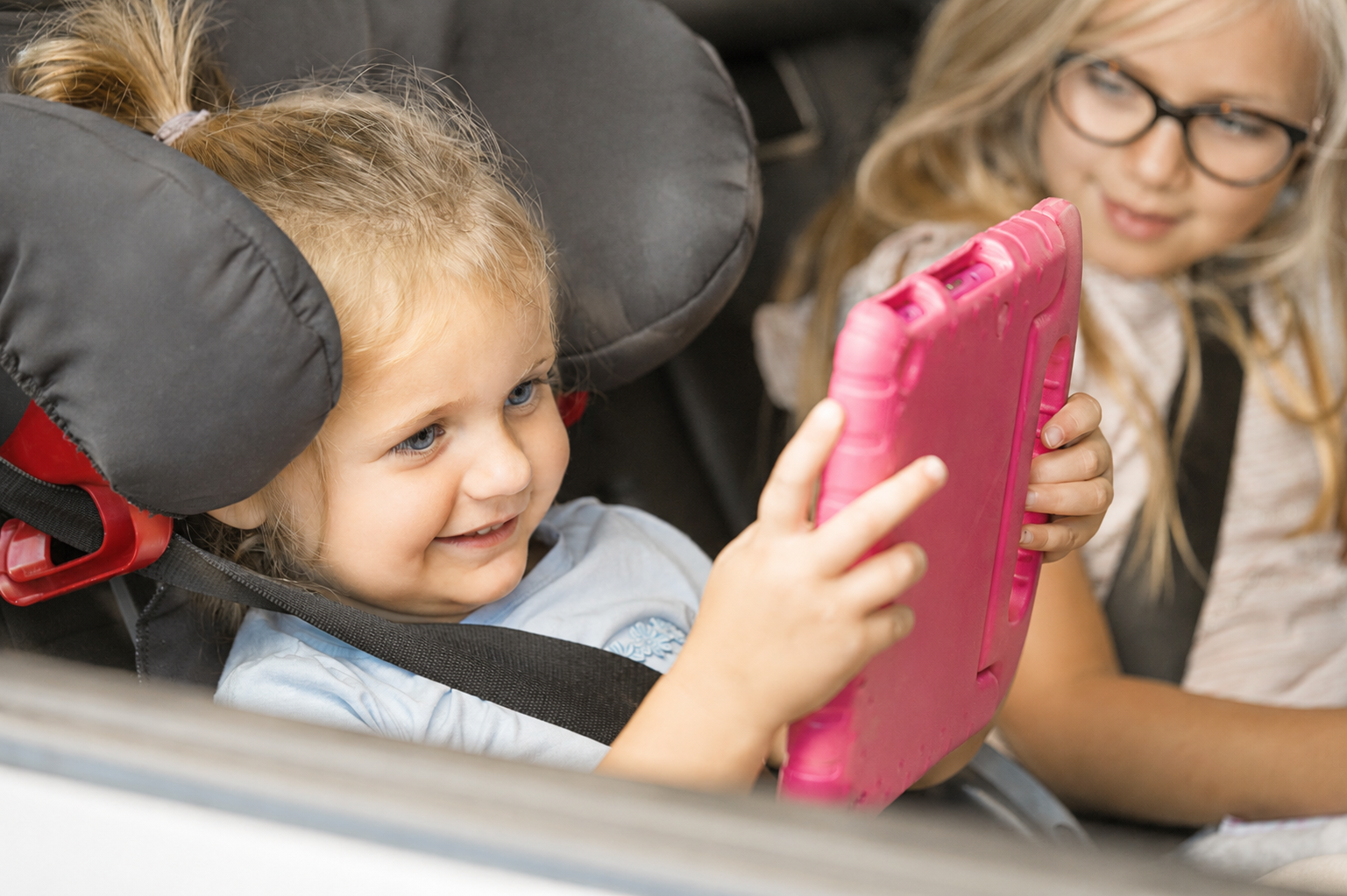 Lille barn kigger på tablet i bilen