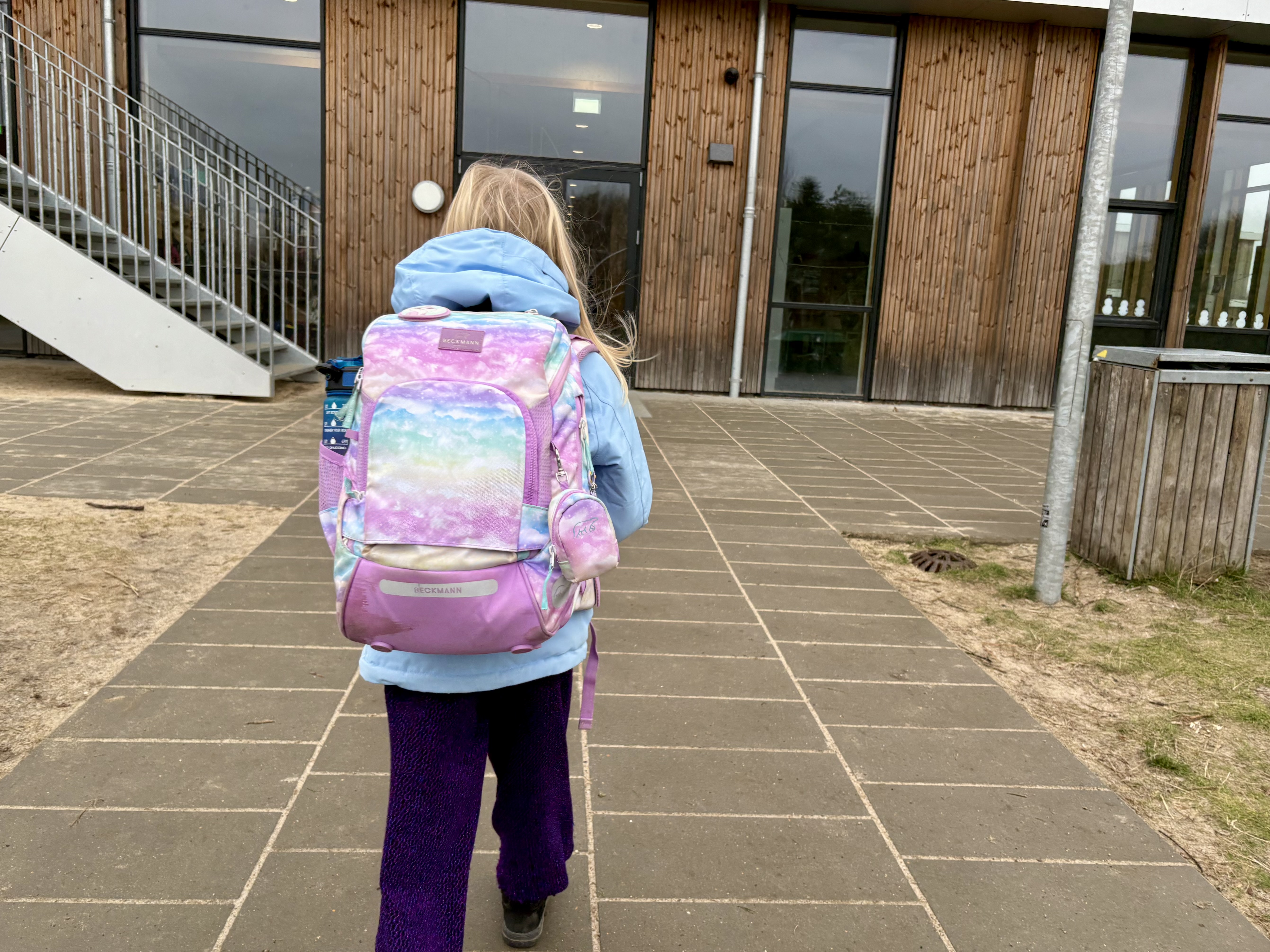 Pigeset bagfra med skoletaske foran skolen