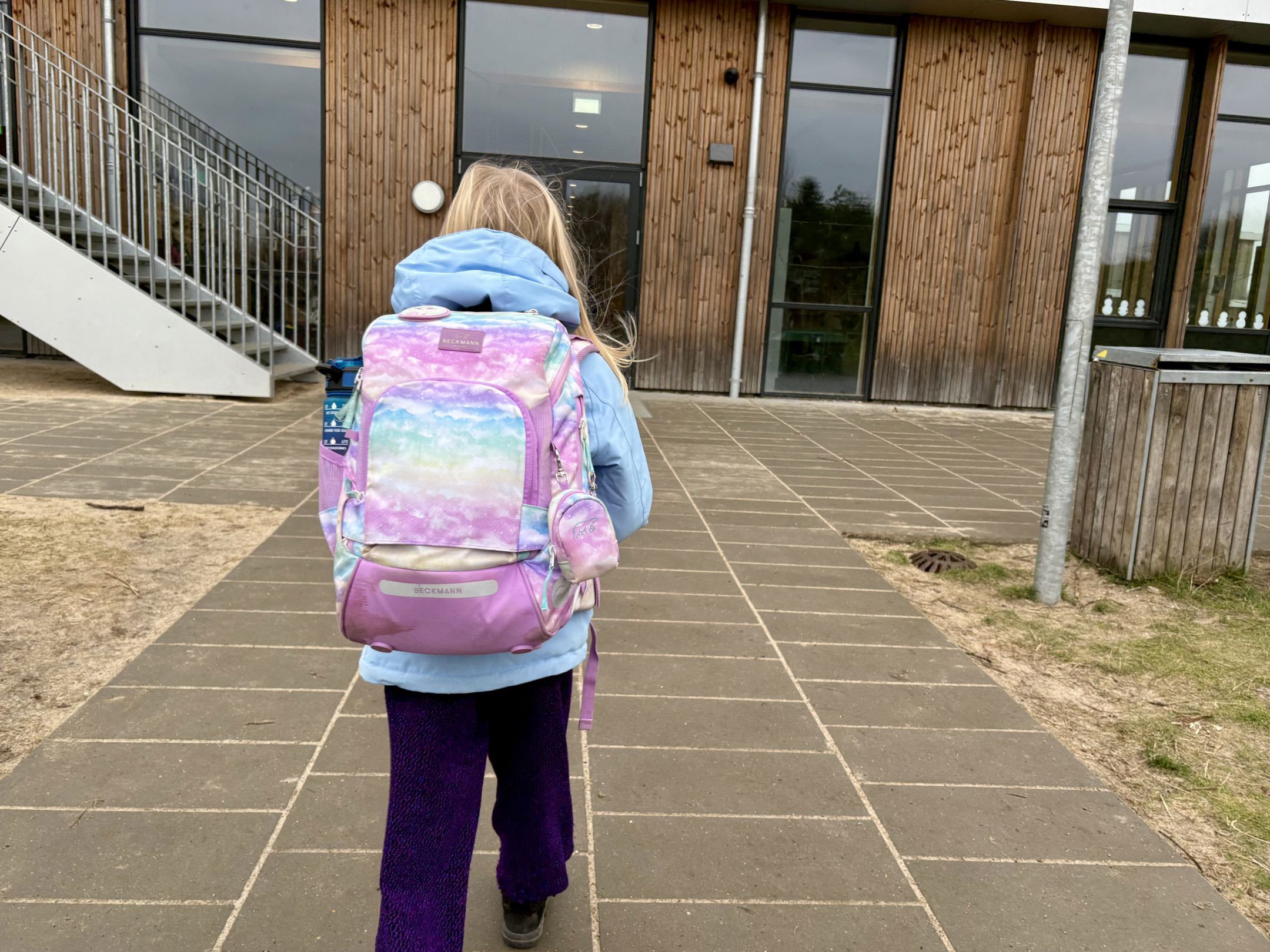 Pigeset bagfra med skoletaske foran skolen