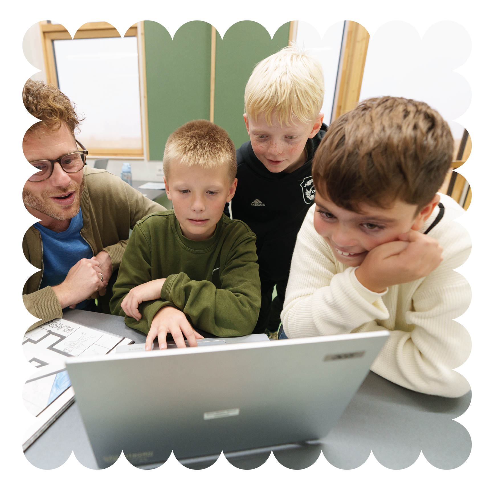 Børn i indskolingen kigger på pc sammen med voksen