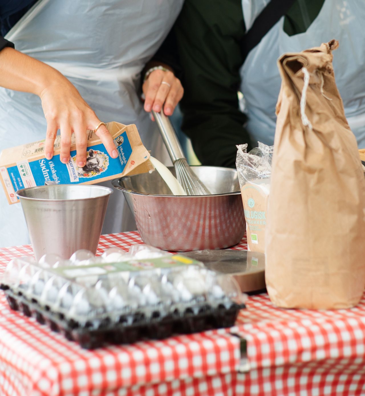 Bord med skål, piskeris, mælk, mel og æg.